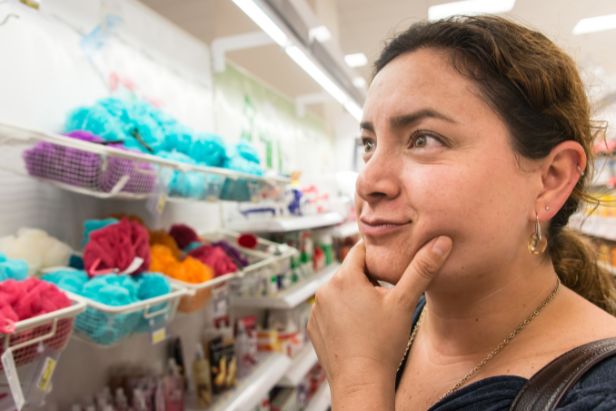 Förvirrad kvinna tittar på produkter i butikshyllan och undrar vilka miljömärkningar man kan lita på